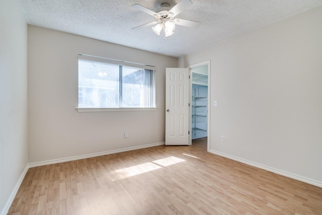511 Windsor Way, Rockwall, TX 75087 - unfurnished bedroom featuring wood finished floors, a textured ceiling, a walk in closet, and baseboards