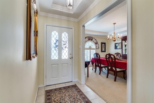 entrance foyer with a chandelier, light tile patterned floors, crown molding, a raised ceiling, and light colored carpet