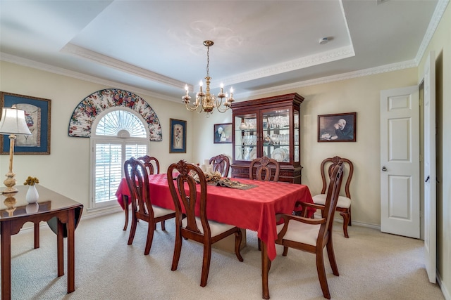 dining room featuring ornamental molding, a tray ceiling, an inviting chandelier, and light carpet