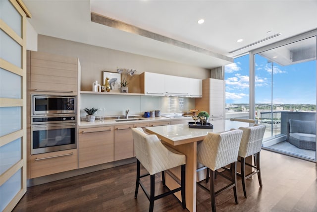 2408 Victory Park Ln Unit 1031, Dallas, TX 75219 - kitchen featuring dark wood-style floors, stainless steel appliances, a breakfast bar, a sink, and a wall of windows