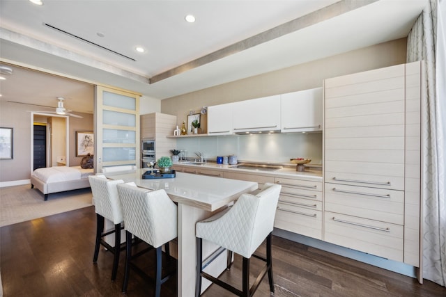 2408 Victory Park Ln Unit 1031, Dallas, TX 75219 - kitchen featuring a breakfast bar, dark wood finished floors, light countertops, black electric cooktop, and a sink