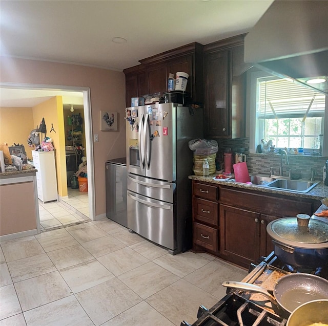 kitchen with stainless steel fridge with ice dispenser, tasteful backsplash, light tile patterned floors, washer / dryer, and a sink