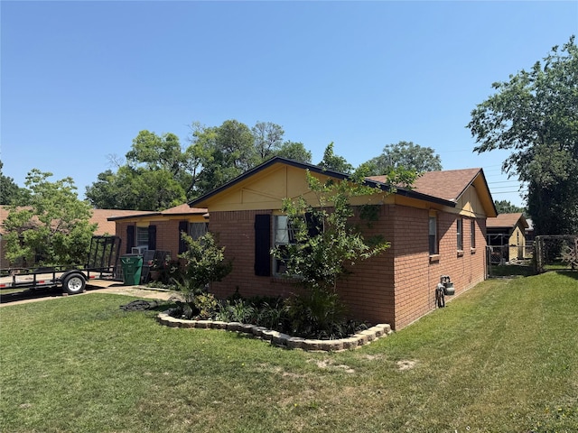 view of property exterior with a yard, a gate, fence, and brick siding
