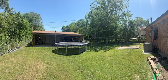view of yard featuring central AC, a fenced backyard, and a trampoline