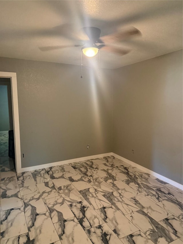 empty room featuring marble finish floor, a textured ceiling, ceiling fan, and baseboards