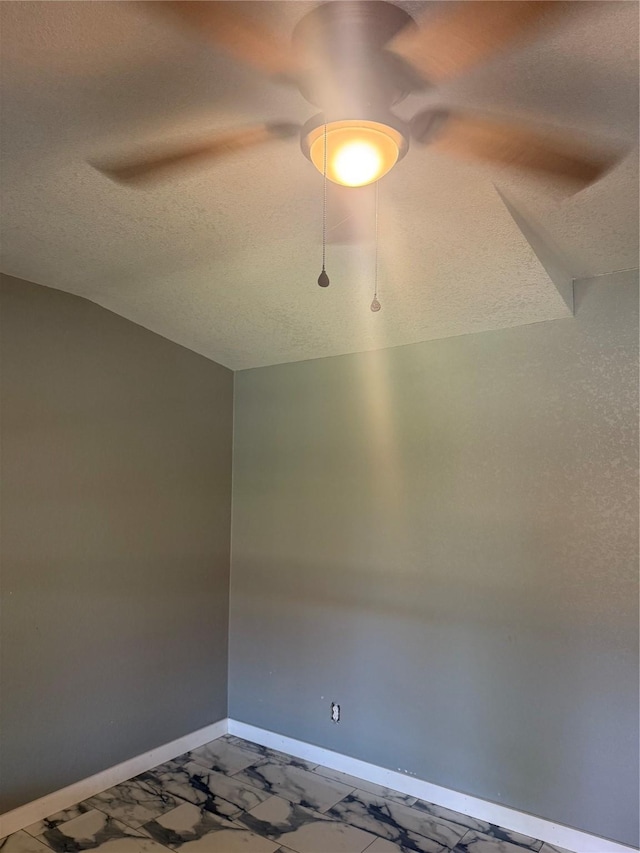 spare room featuring a textured ceiling and baseboards