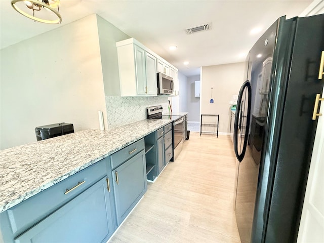 1901 SE 12th St, Mineral Wells, TX 76067 - kitchen with stainless steel appliances, light wood finished floors, recessed lighting, blue cabinetry, and tasteful backsplash