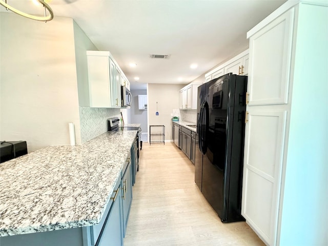 1901 SE 12th St, Mineral Wells, TX 76067 - kitchen featuring appliances with stainless steel finishes, light wood-style flooring, tasteful backsplash, white cabinets, and recessed lighting