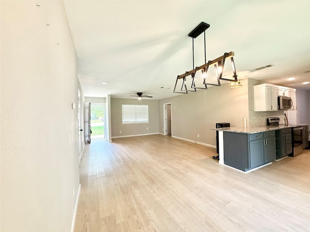 1901 SE 12th St, Mineral Wells, TX 76067 - kitchen featuring stainless steel microwave, baseboards, light stone countertops, ceiling fan, and light wood-style floors