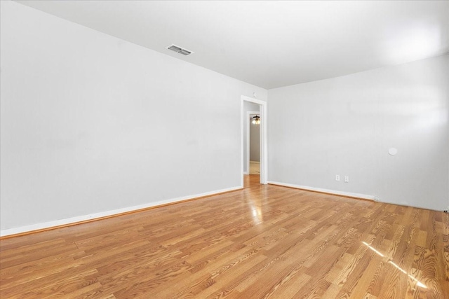 unfurnished room featuring visible vents, light wood-style flooring, and baseboards