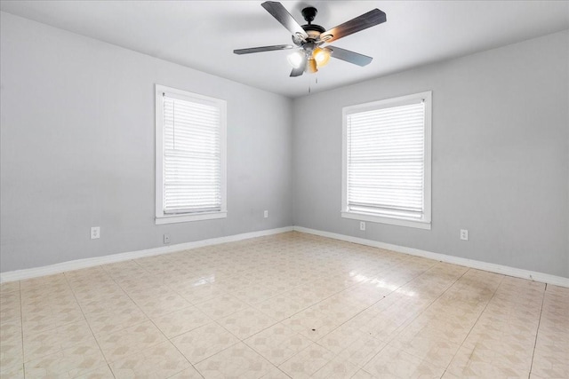 spare room with ceiling fan and baseboards