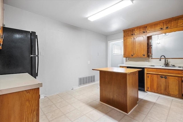 kitchen with a sink, visible vents, light countertops, and black appliances