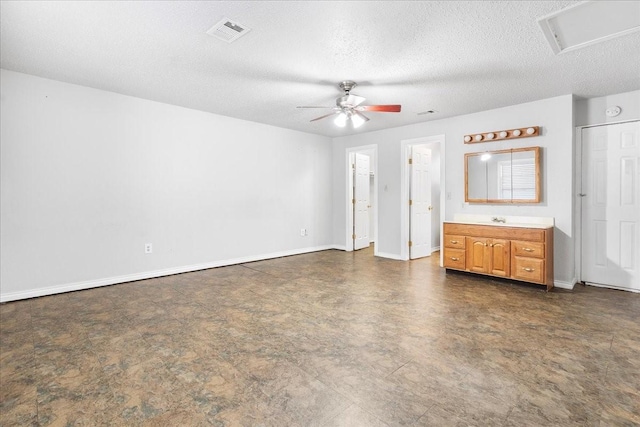 unfurnished bedroom with baseboards, a textured ceiling, a ceiling fan, visible vents, and a sink