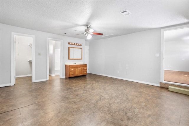 unfurnished living room with visible vents, ceiling fan, baseboards, and a textured ceiling