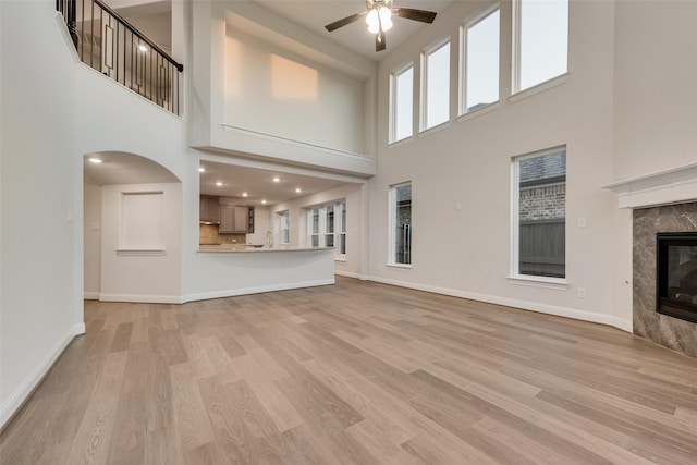 6926 Prairieside Trl, Prairie Ridge, TX 76084 - unfurnished living room with a high ceiling, a ceiling fan, baseboards, light wood-style floors, and a premium fireplace