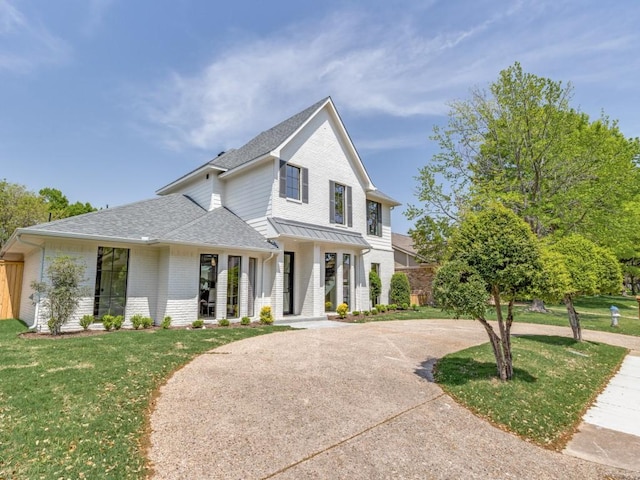 6909 Middle Cove Dr, Dallas, TX 75248 - view of front facade featuring a shingled roof, brick siding, a front lawn, and curved driveway