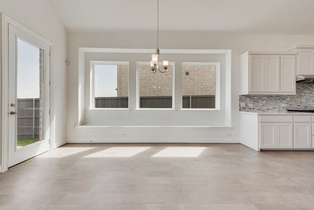 unfurnished dining area featuring a chandelier and light wood-style floors