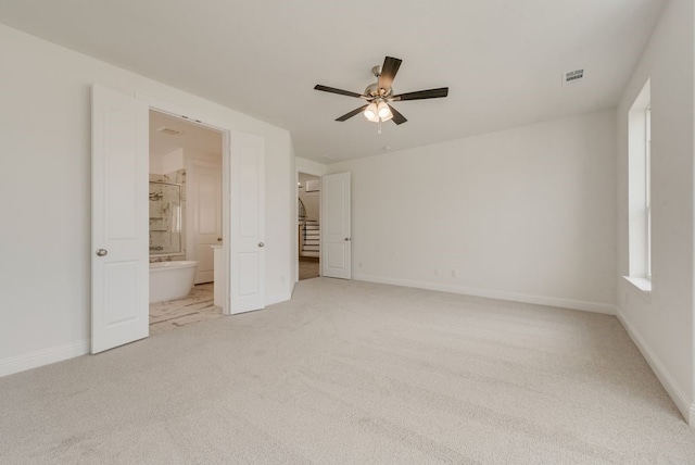 unfurnished bedroom featuring light carpet, baseboards, ensuite bathroom, and ceiling fan