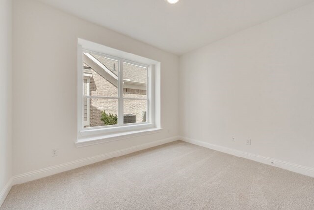 unfurnished room with light colored carpet and baseboards