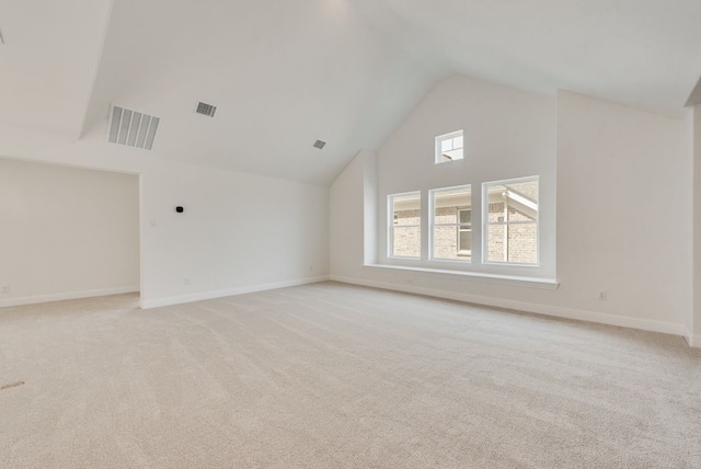 empty room with high vaulted ceiling, light colored carpet, and baseboards