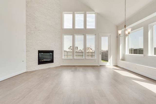 unfurnished living room featuring high vaulted ceiling, a chandelier, wood finished floors, and a fireplace