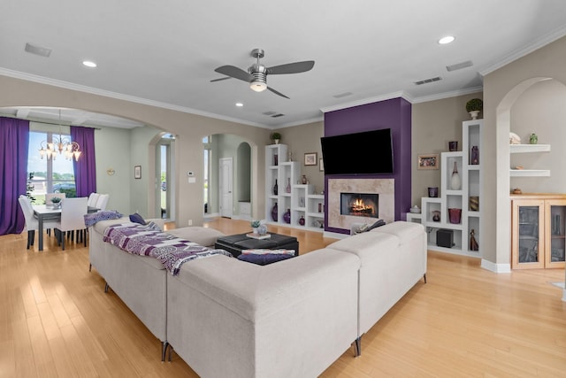 living room with recessed lighting, a premium fireplace, light wood-type flooring, and ceiling fan with notable chandelier