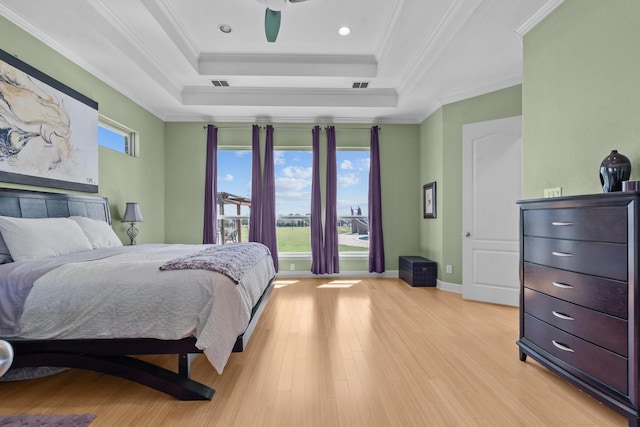 bedroom featuring light wood-type flooring, ornamental molding, visible vents, and a raised ceiling