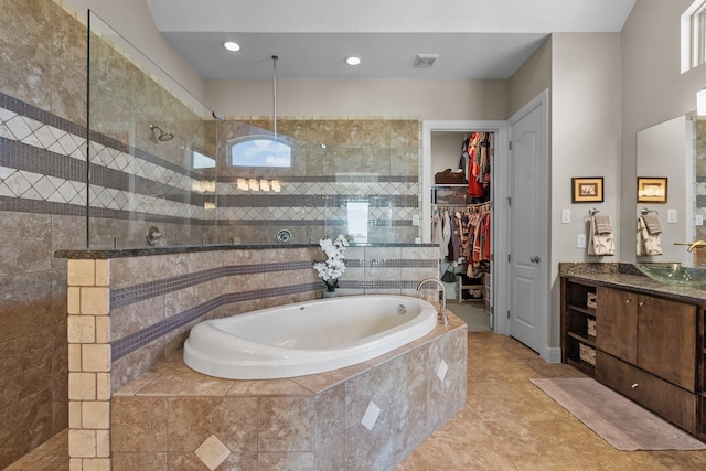 bathroom with tile patterned floors, a bath, a spacious closet, vanity, and a walk in shower
