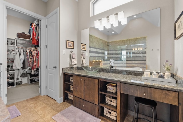 bathroom with a spacious closet, vanity, tile patterned flooring, and a walk in shower