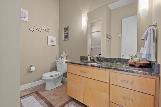 bathroom with toilet, a shower with door, vanity, baseboards, and tile patterned flooring