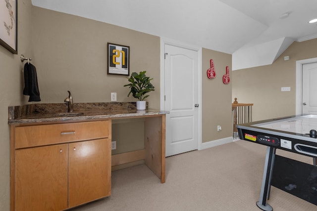 interior space featuring a sink, stone countertops, baseboards, light colored carpet, and lofted ceiling