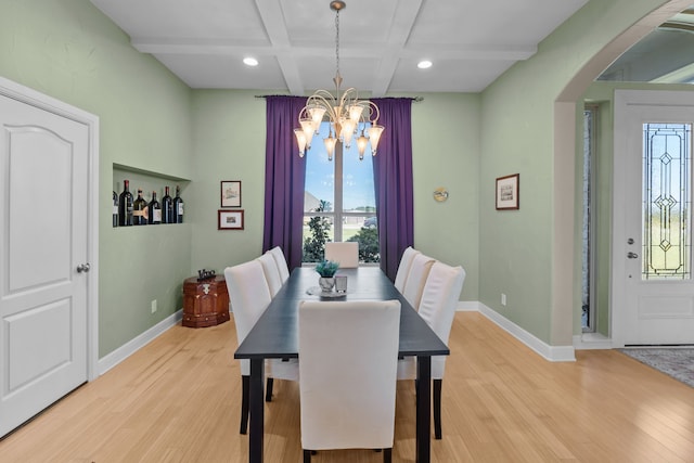 dining area with arched walkways, light wood-style flooring, baseboards, and an inviting chandelier