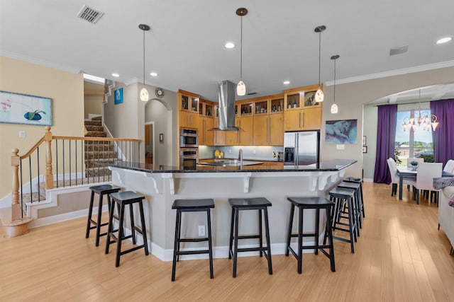 kitchen with stainless steel appliances, visible vents, light wood-style floors, exhaust hood, and ornamental molding