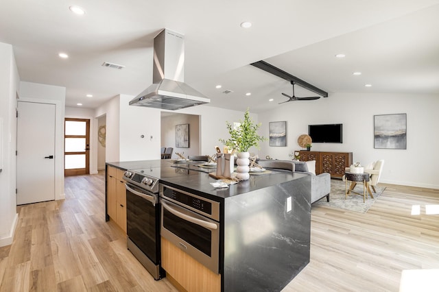 5629 Terry St, The Colony, TX 75056 - kitchen featuring light brown cabinetry, stainless steel range with electric stovetop, island range hood, open floor plan, and light wood-style floors