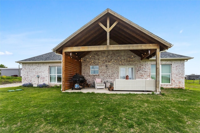 back of house with a lawn, brick siding, a patio, and a shingled roof