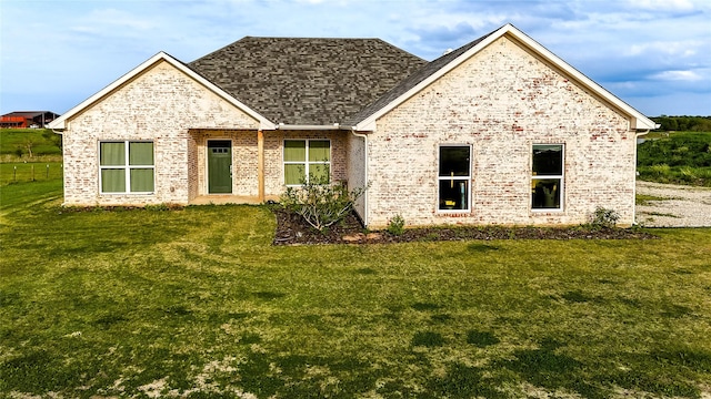 view of front facade featuring a front lawn, brick siding, and a shingled roof