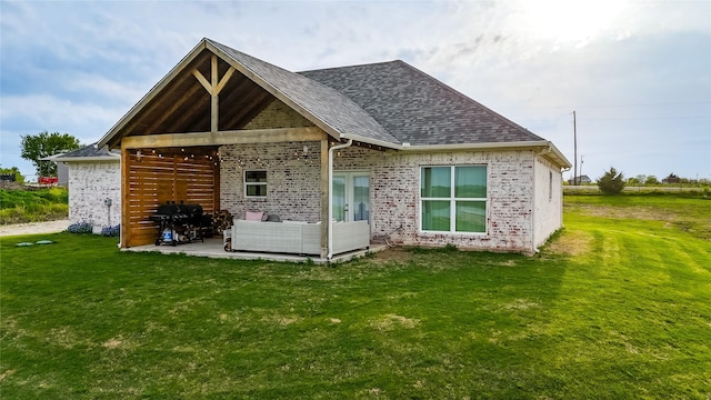 back of house featuring roof with shingles, an outdoor living space, a yard, and a patio