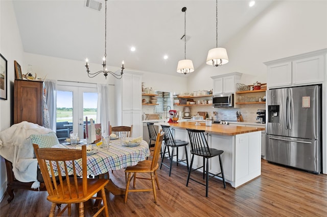 dining room featuring french doors, wood finished floors, visible vents, and an inviting chandelier