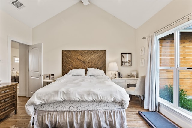 bedroom with wood finished floors, visible vents, high vaulted ceiling, and multiple windows