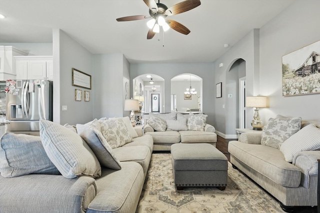 1057 Canterbury Ln, Forney, TX 75126 - living room featuring arched walkways, a chandelier, light wood-type flooring, ceiling fan, and baseboards