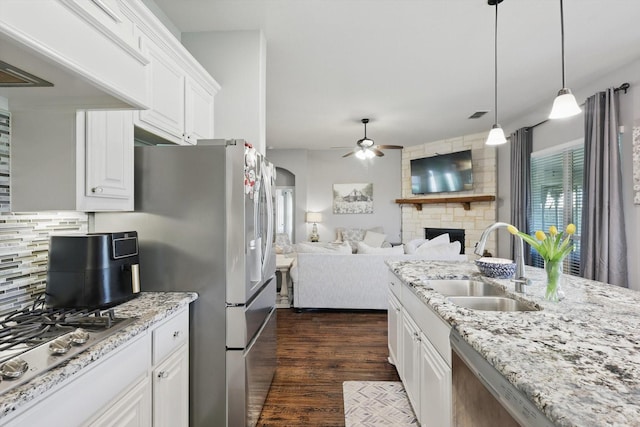 1057 Canterbury Ln, Forney, TX 75126 - kitchen featuring a sink, a ceiling fan, stainless steel appliances, decorative backsplash, and a fireplace