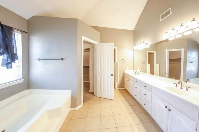 bathroom featuring visible vents, a sink, vaulted ceiling, tile patterned floors, and a garden tub