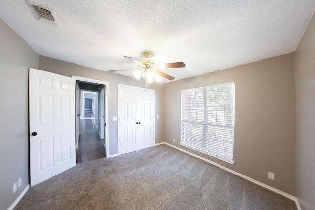 unfurnished bedroom featuring visible vents, baseboards, a closet, a textured ceiling, and carpet floors
