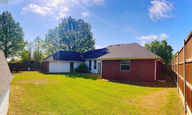 rear view of house featuring roof with shingles, brick siding, a fenced backyard, and a lawn