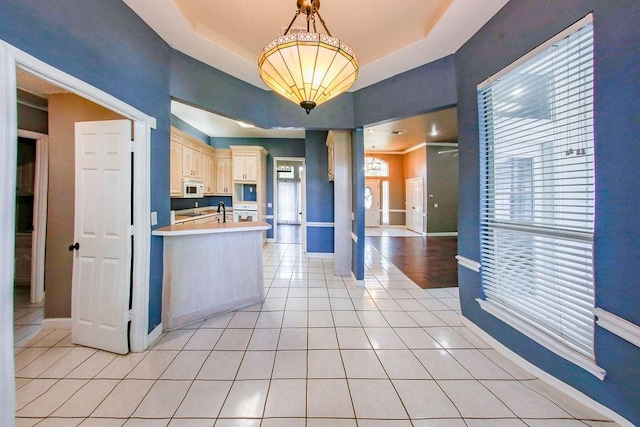 kitchen featuring light countertops, light tile patterned floors, white microwave, and baseboards