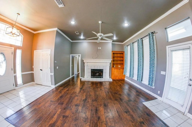 unfurnished living room with crown molding, visible vents, ceiling fan, and a fireplace