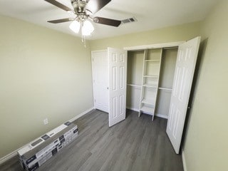 unfurnished bedroom featuring a closet, baseboards, visible vents, ceiling fan, and wood finished floors