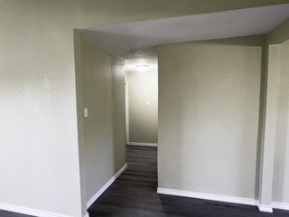 hall with dark wood-style flooring and baseboards