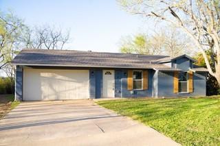ranch-style home with a garage, driveway, and a front lawn