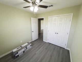 unfurnished bedroom featuring wood finished floors, baseboards, a closet, and visible vents
